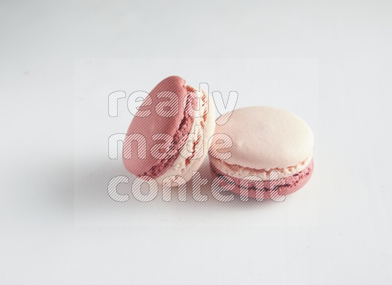 45º Shot of two Pink Litchi Raspberry macarons on white background