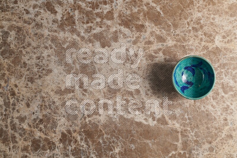 A multicolored pottery bowl on beige marble background