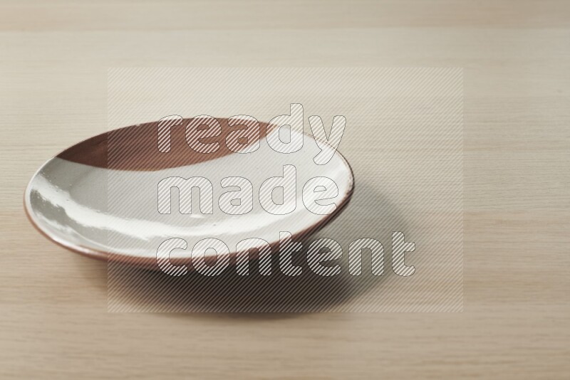 A multicolored pottery plate on light wooden background