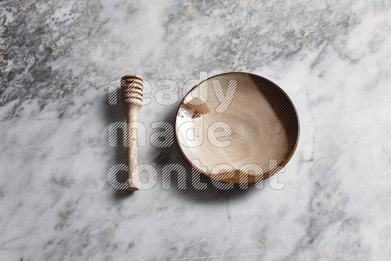 Multicolored Pottery Plate with wooden honey handle on the side with grey marble flooring, 65 degree angle