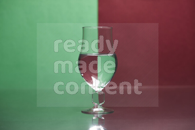 The image features a clear glassware filled with water, set against green and dark red background