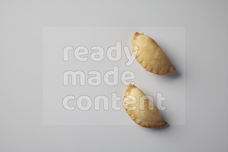 Two fried sambosa from a top angle on a white background
