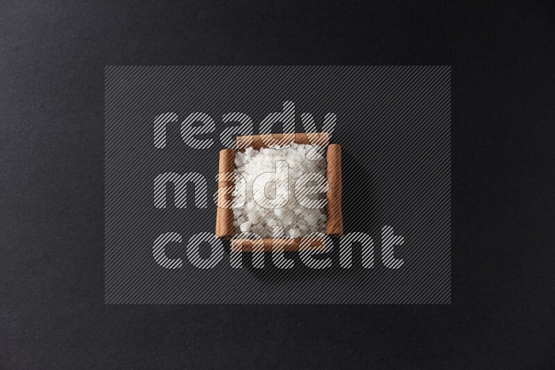 A single square of cinnamon sticks full of salt on black flooring