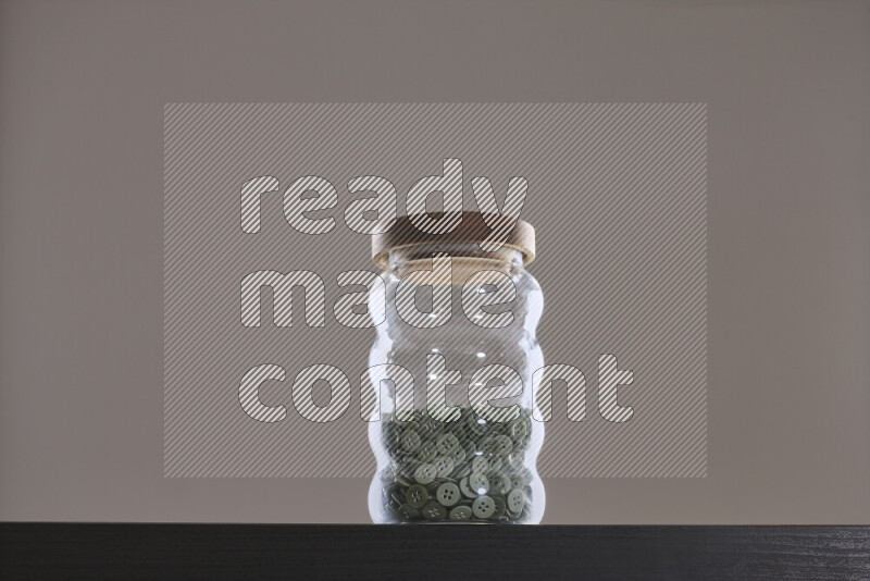 أزرار متنوعة في وعاء زجاجي علي خلفية سوداء