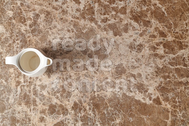 Top View Shot Of A Ceramic Milk Jug On beige Marble Flooring