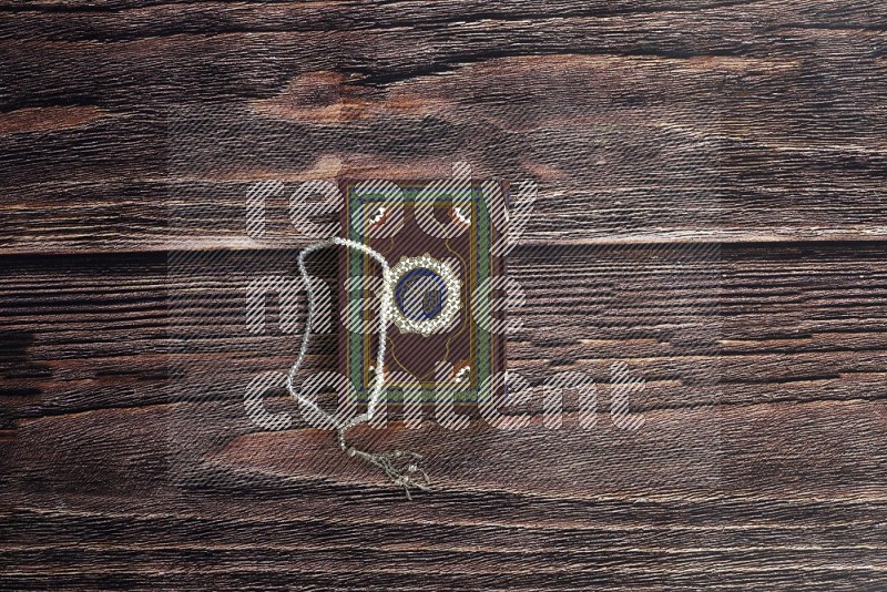 Quran with a prayer beads on wooden background