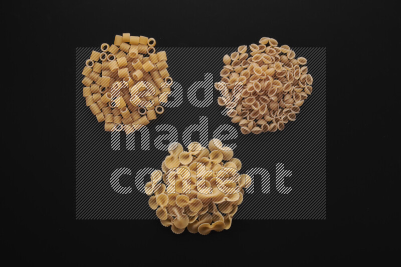 Different pasta types in bunches on black background
