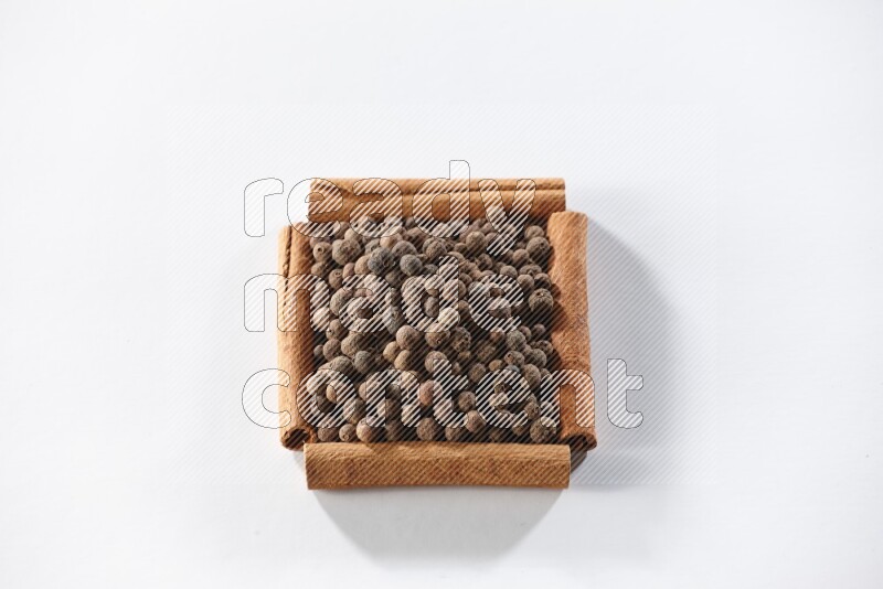 A single square of cinnamon sticks full of allspice on white flooring