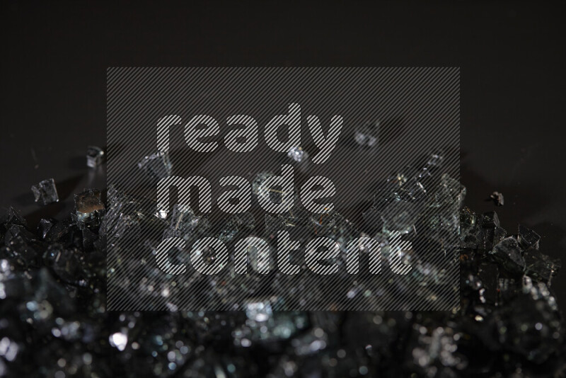 Transparent black fragments of glass scattered on a black background