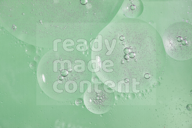 Close-ups of abstract oil bubbles on water surface in shades of green