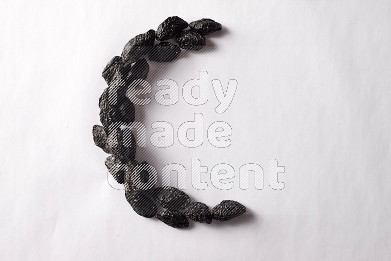 Dried plums in a crescent shape on white background
