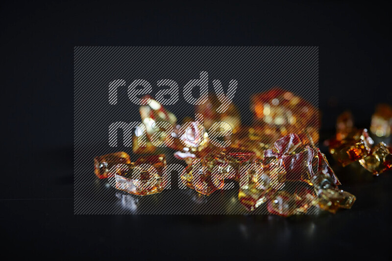 Transparent orange fragments of glass scattered on a black background