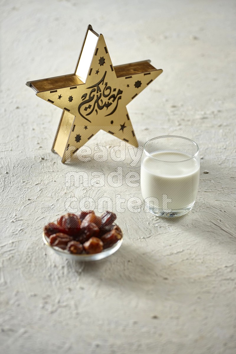 A wooden golden star lantern with different drinks, dates, nuts, prayer beads and quran on textured white background