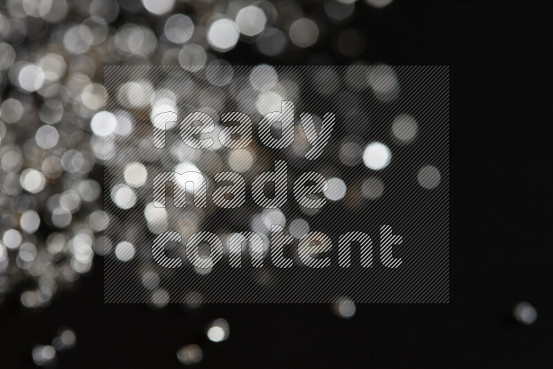 قطع زجاجية فضية لامعة متناثرة على خلفية سوداء