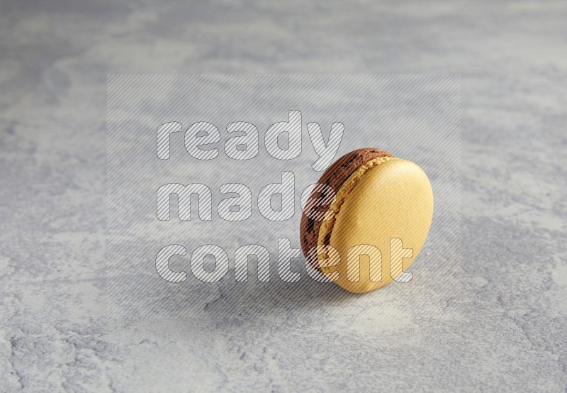 45º Shot of Yellow and Brown Chai Latte macaron on white  marble background