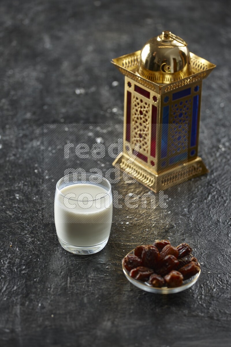 A golden lantern with different drinks, dates, nuts, prayer beads and quran on textured black background