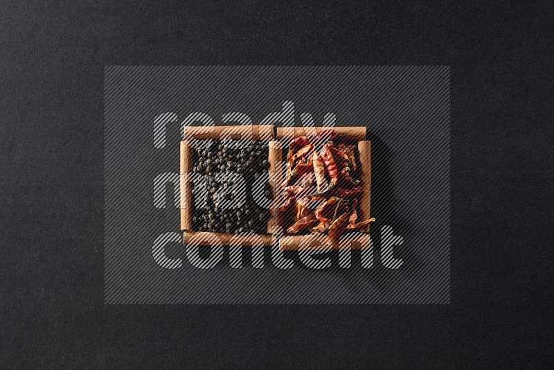 2 squares of cinnamon sticks full of chilis and black peppers on black flooring