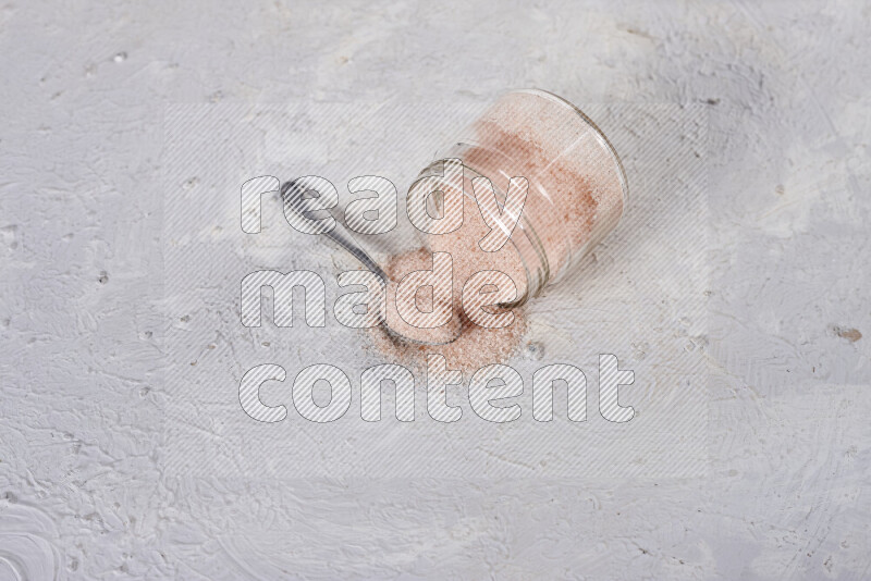 A glass jar full of fine himalayan salt on white background