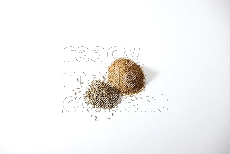 Cumin seeds and cumin powder on white flooring