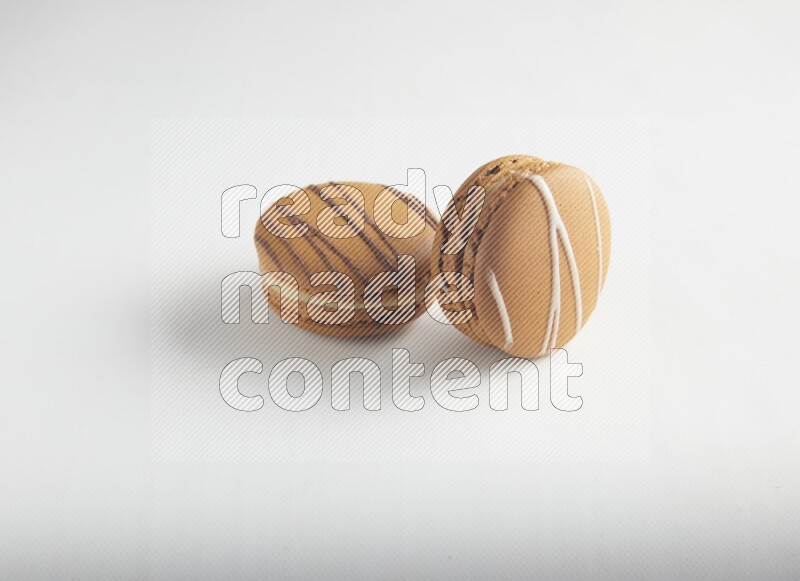 45º Shot of of two assorted Brown Irish Cream, and light brown  Almond Cream macarons on white background