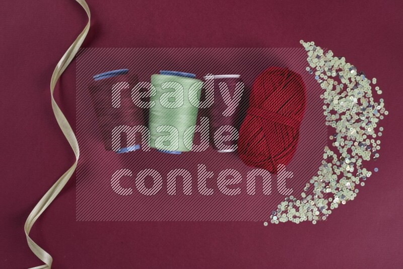 A green and red collection of sewing and tailoring tools arranged on a red background