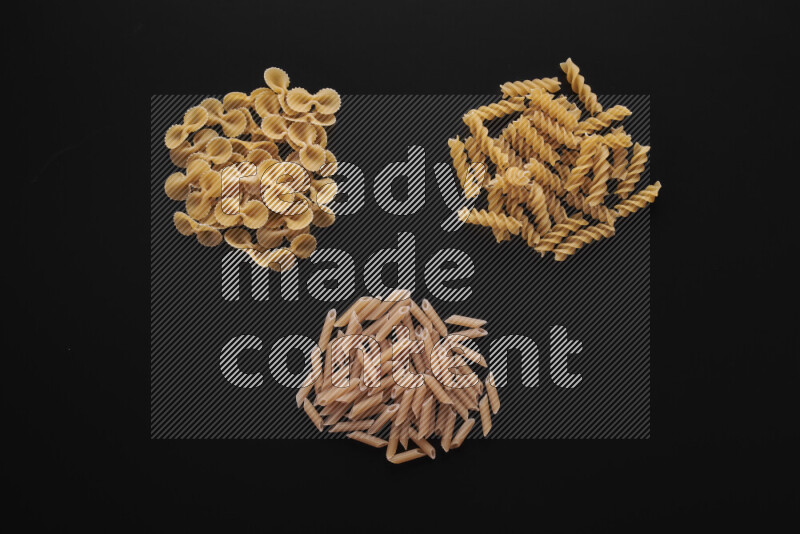 Different pasta types in bunches on black background