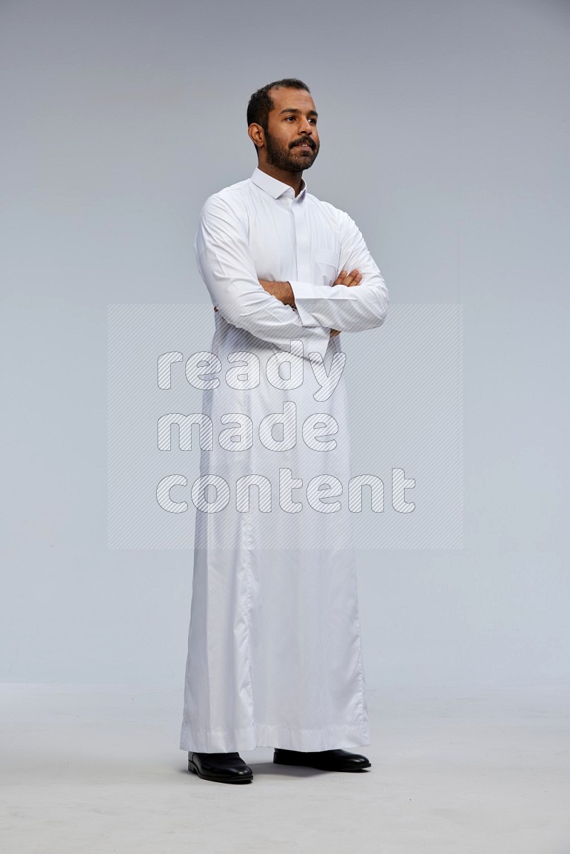 Saudi man wearing Thob standing with crossed arms on Gray background