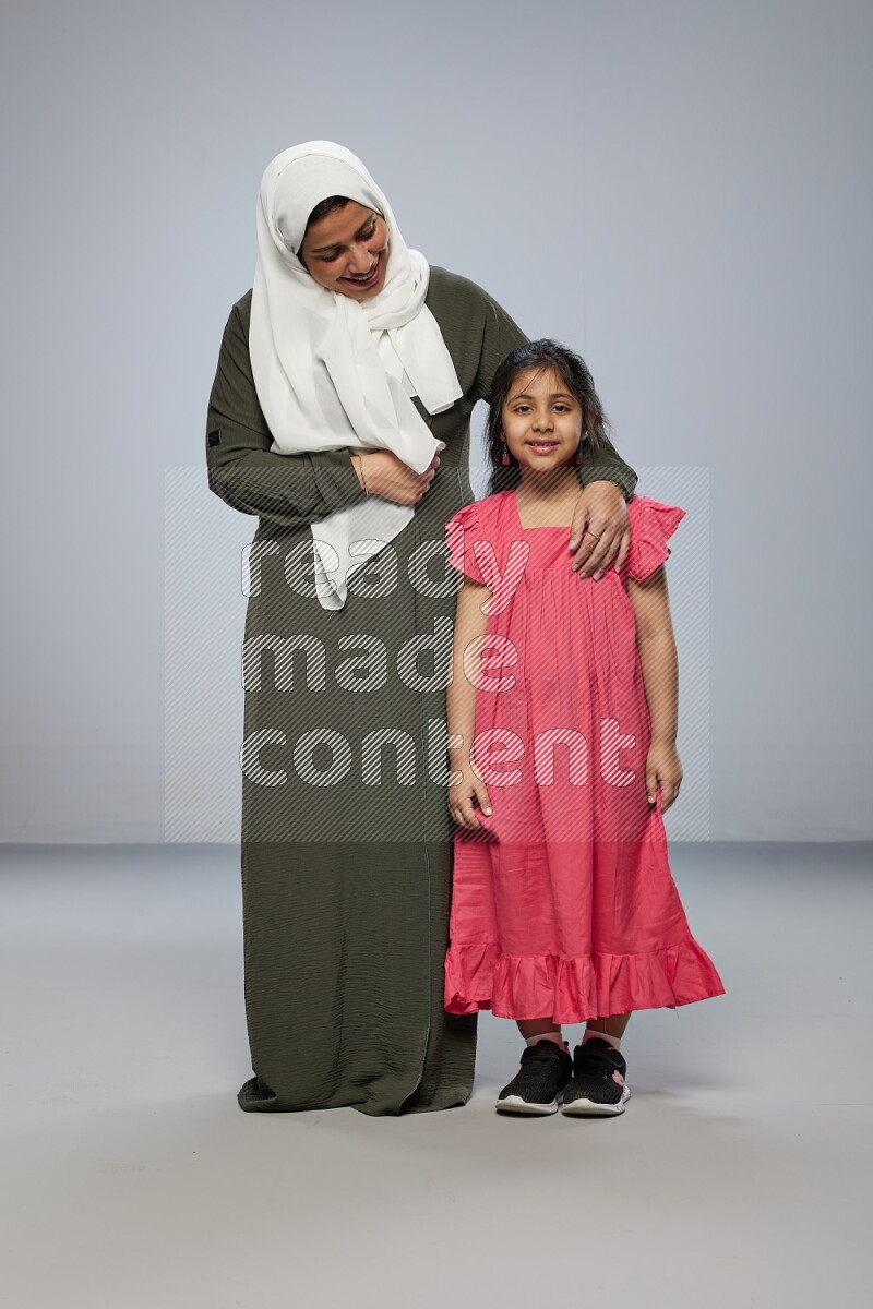 A girl and her mother interacting with the camera on gray background