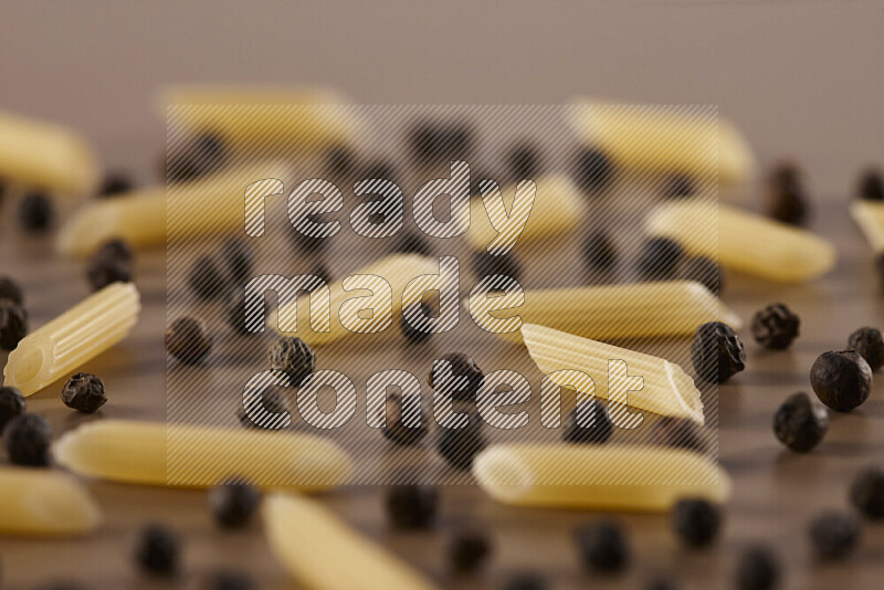 Raw pasta with different ingredients such as cherry tomatoes, garlic, onions, red chilis, black pepper, white pepper, bay laurel leaves, rosemary and cardamom on beige background