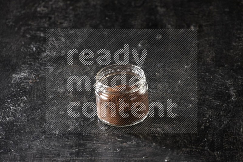 وعاء زجاجي ممتلئ ببودرة القرنفل على أرضية سوداء
