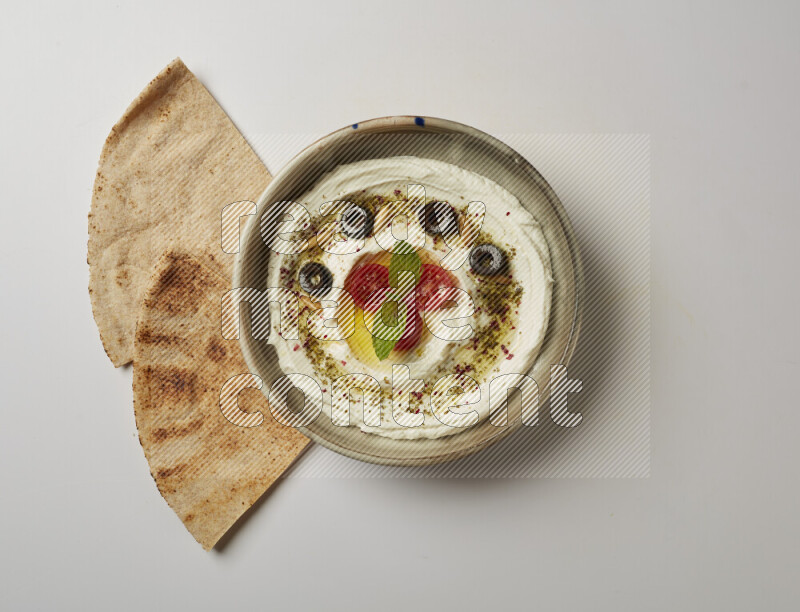 Lebnah garnished with cherry tomato, mint, olives & pine nuts in a grey pottery plate on a white background