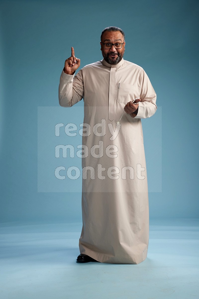 Saudi Man without shimag Standing Interacting with the camera on blue background