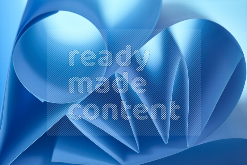 An artistic display of paper folds creating a harmonious blend of geometric shapes, highlighted by soft lighting in blue tones