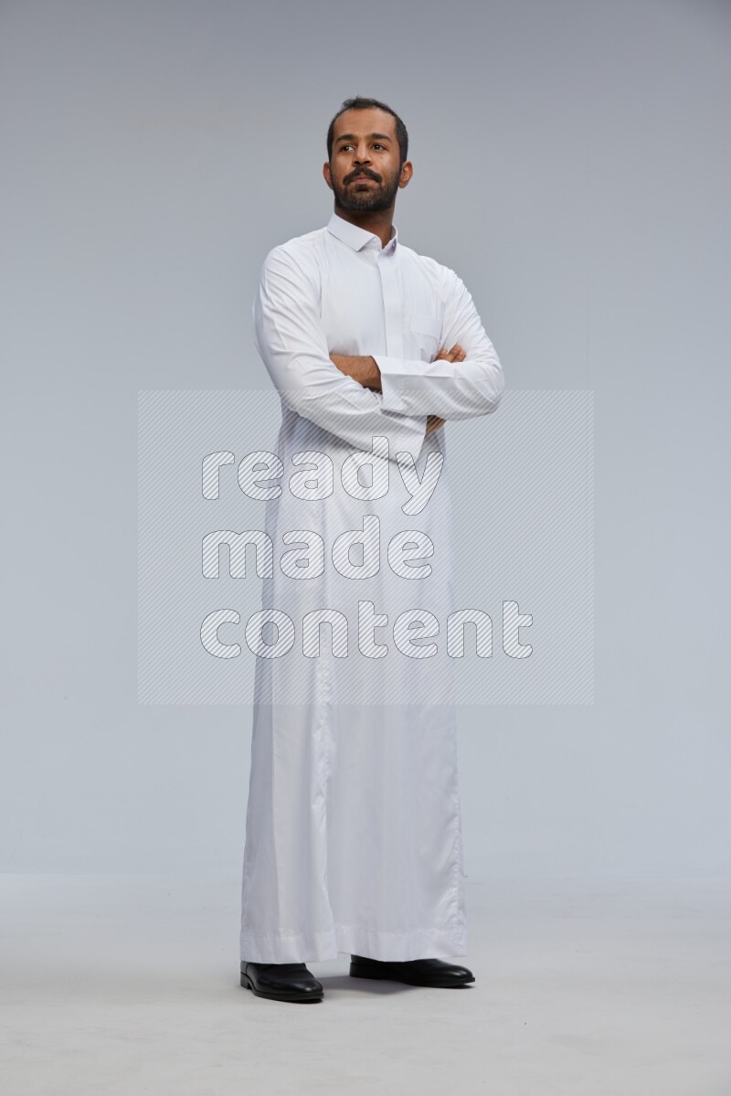 Saudi man wearing Thob standing with crossed arms on Gray background
