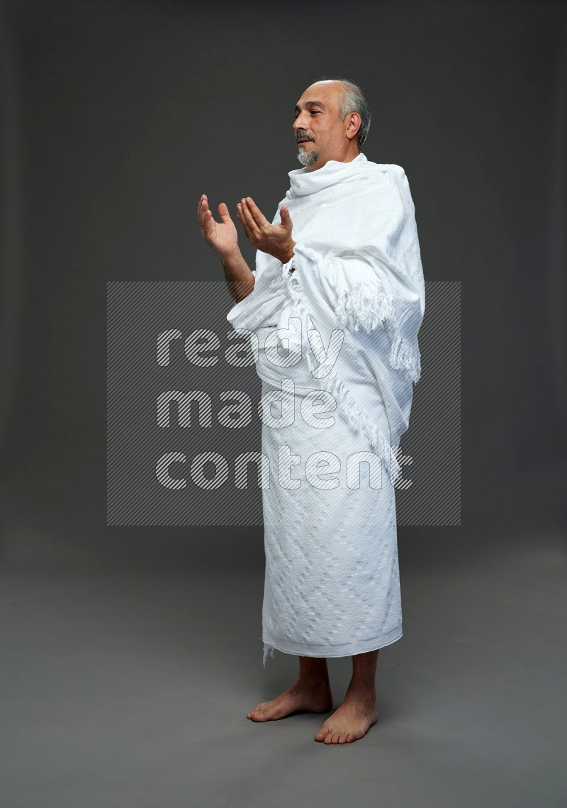 A man wearing Ehram Standing dua'a on gray background