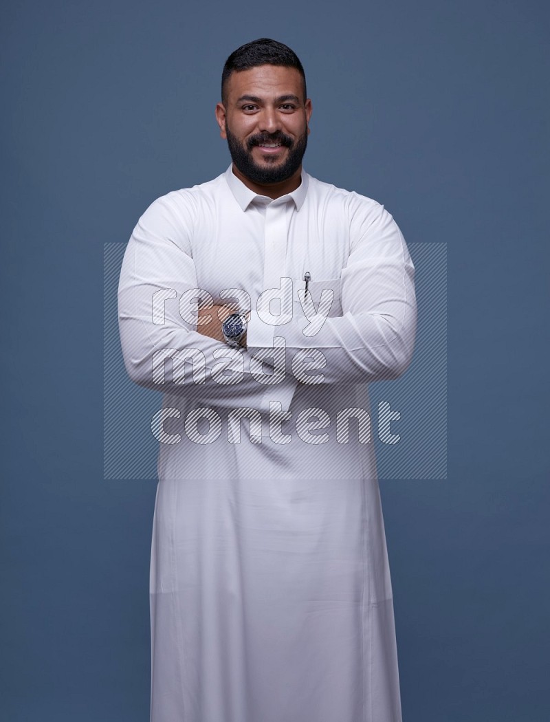 A man Posing in Blue Background wearing a Saudi Thob