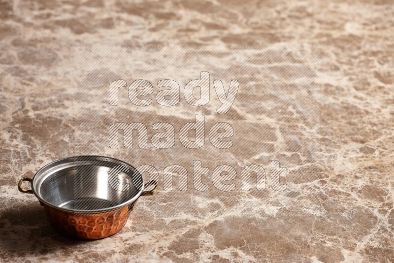 A small copper pot on beige marble background