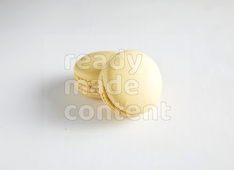 45º Shot of two Yellow Vanilla macarons on white background