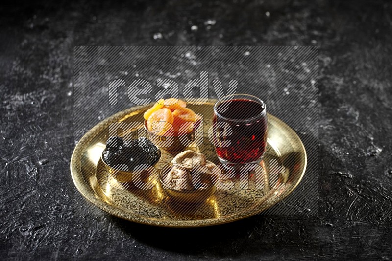 Dried fruits in metal bowls with Hibiscus on a tray in dark setup