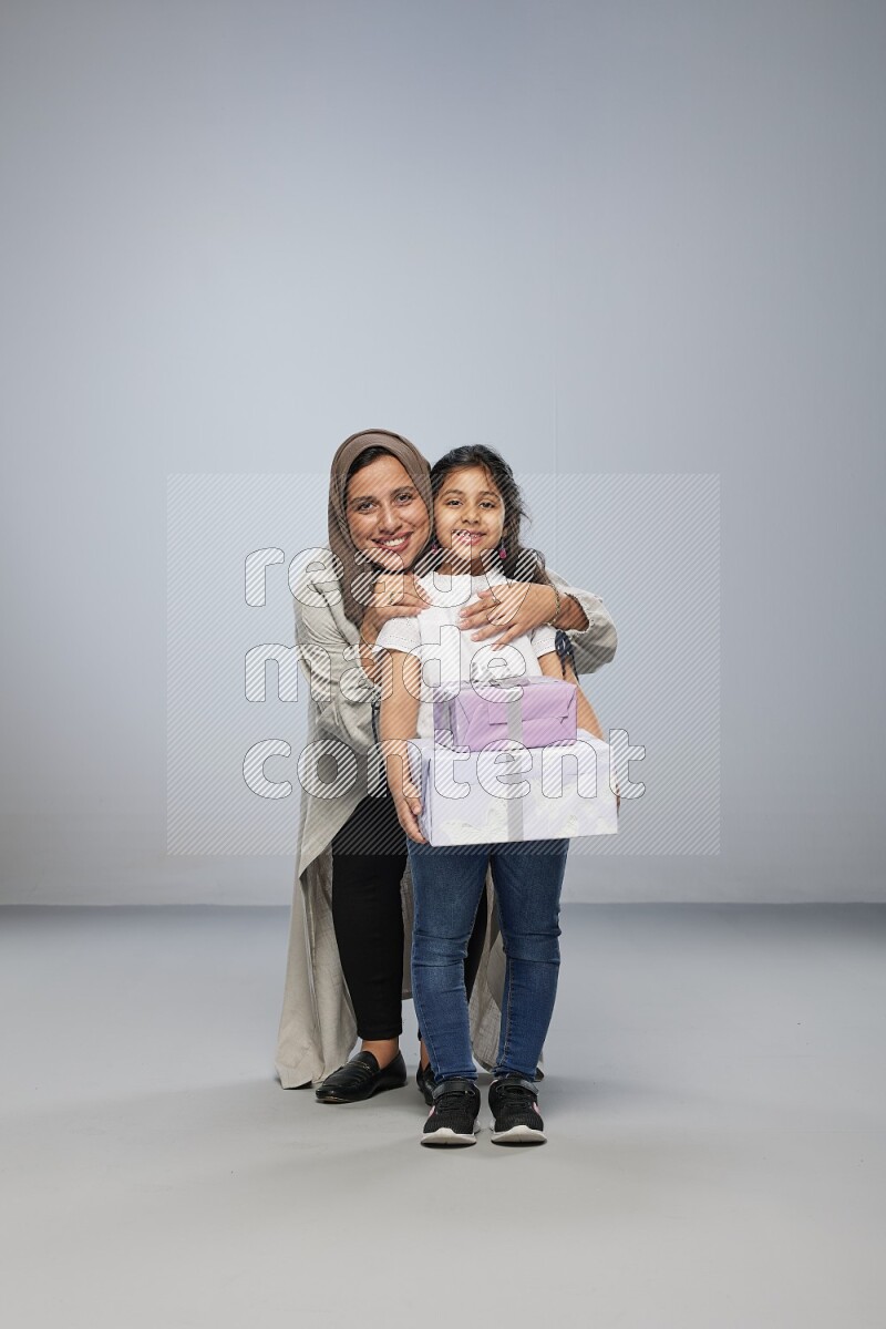 A girl giving a gift to her mother on gray background