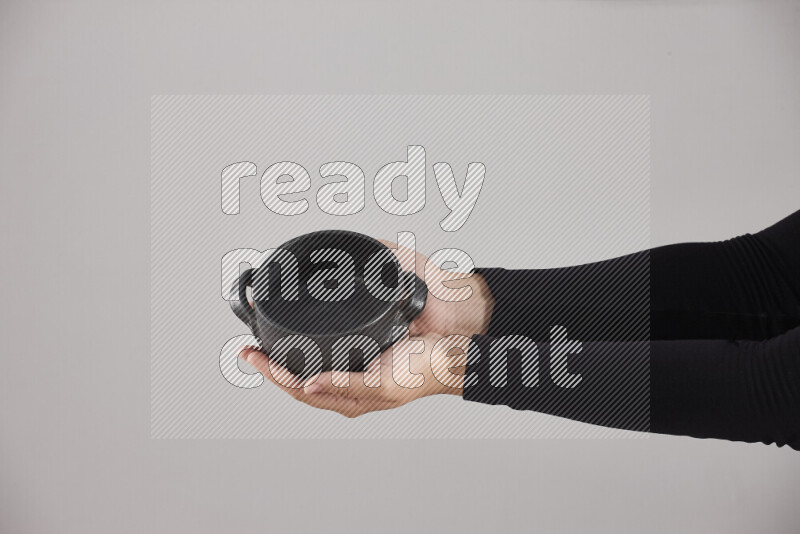 A woman in black abaya holding different pottery essentials in different positions
