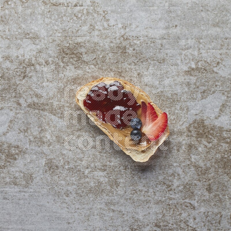 open faced peanut butter sandwich with jam, strawberries and blueberries & chia on a  grey textured background