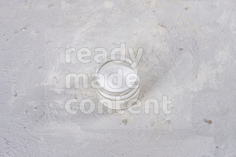 A glass jar full of fine table salt on white background