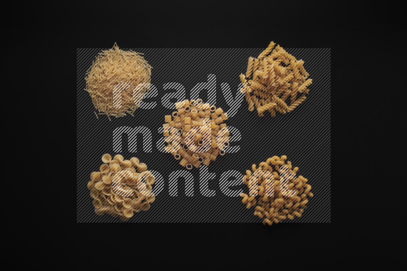 Different pasta types in bunches on black background
