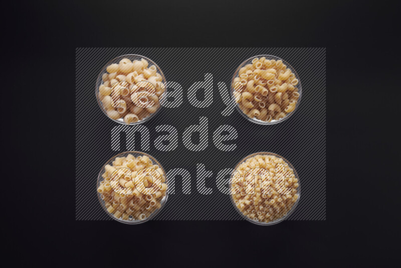 أنواع مختلفة من المعكرونة في وعاء زجاجي علي خلفية سوداء