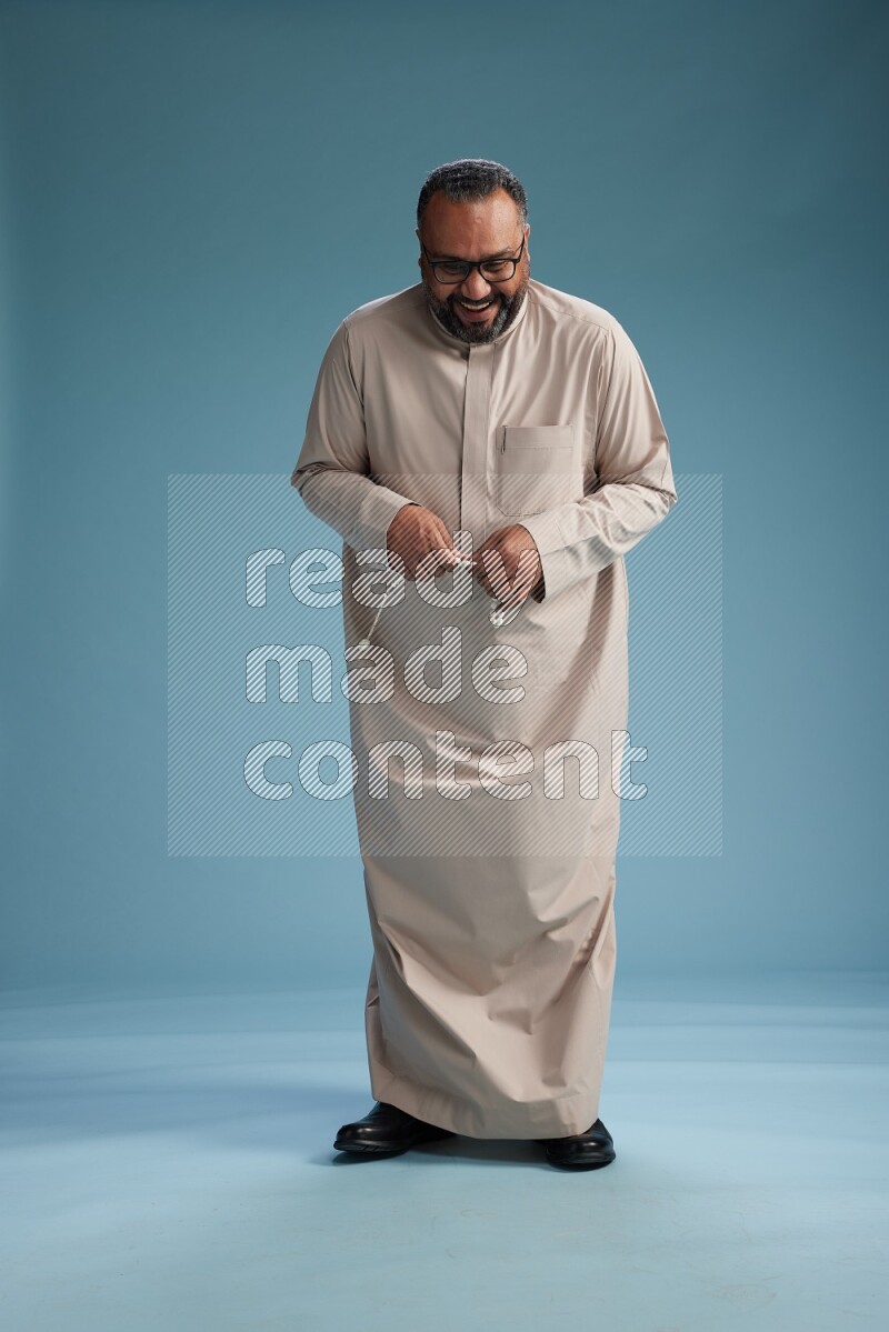 Saudi Man without shimag Standing Interacting with the camera on blue background