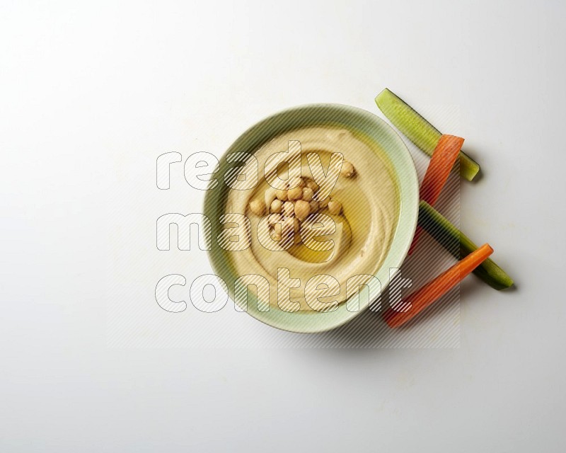 Hummus in a green plate garnished with roasted chickpeas  on a white background