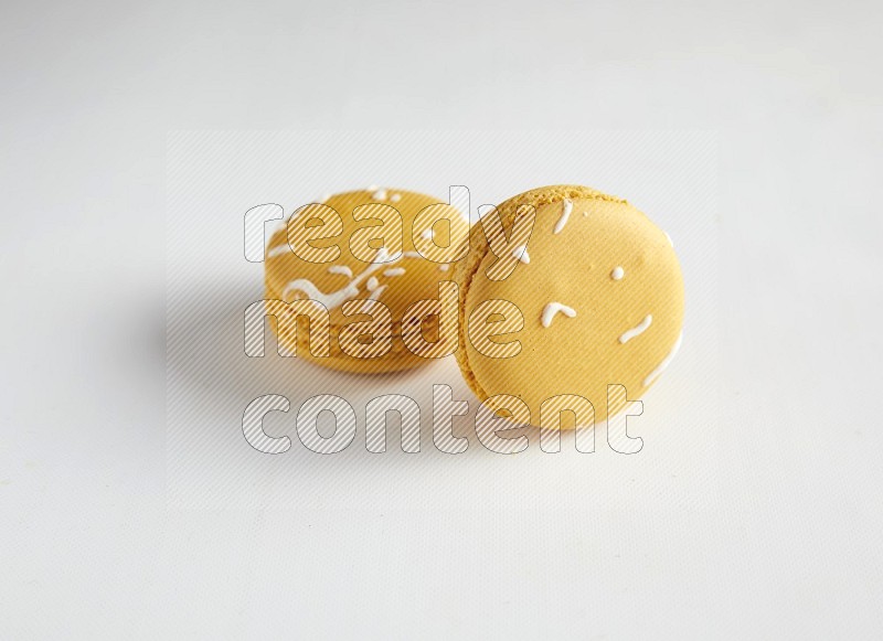 45º Shot of two Yellow Piña Colada macarons on white background