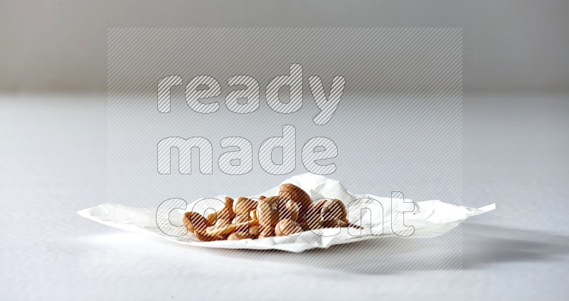 Cashews on a crumpled piece of paper on a white background in different angles
