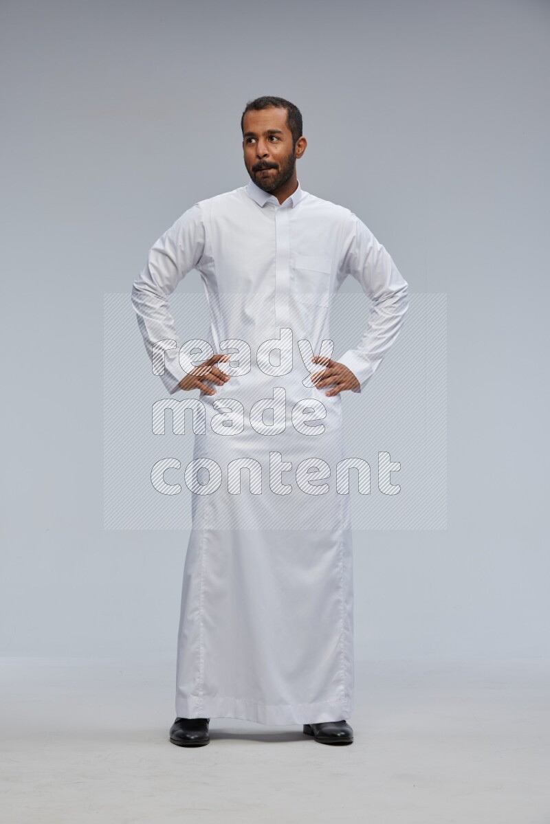 Saudi man Wearing Thob standing interacting with the camera on Gray background